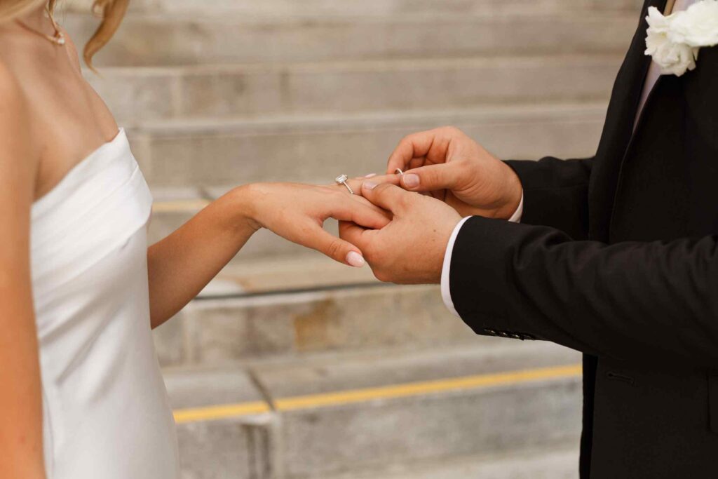 Close up of groom placing wedding band on bride's finger