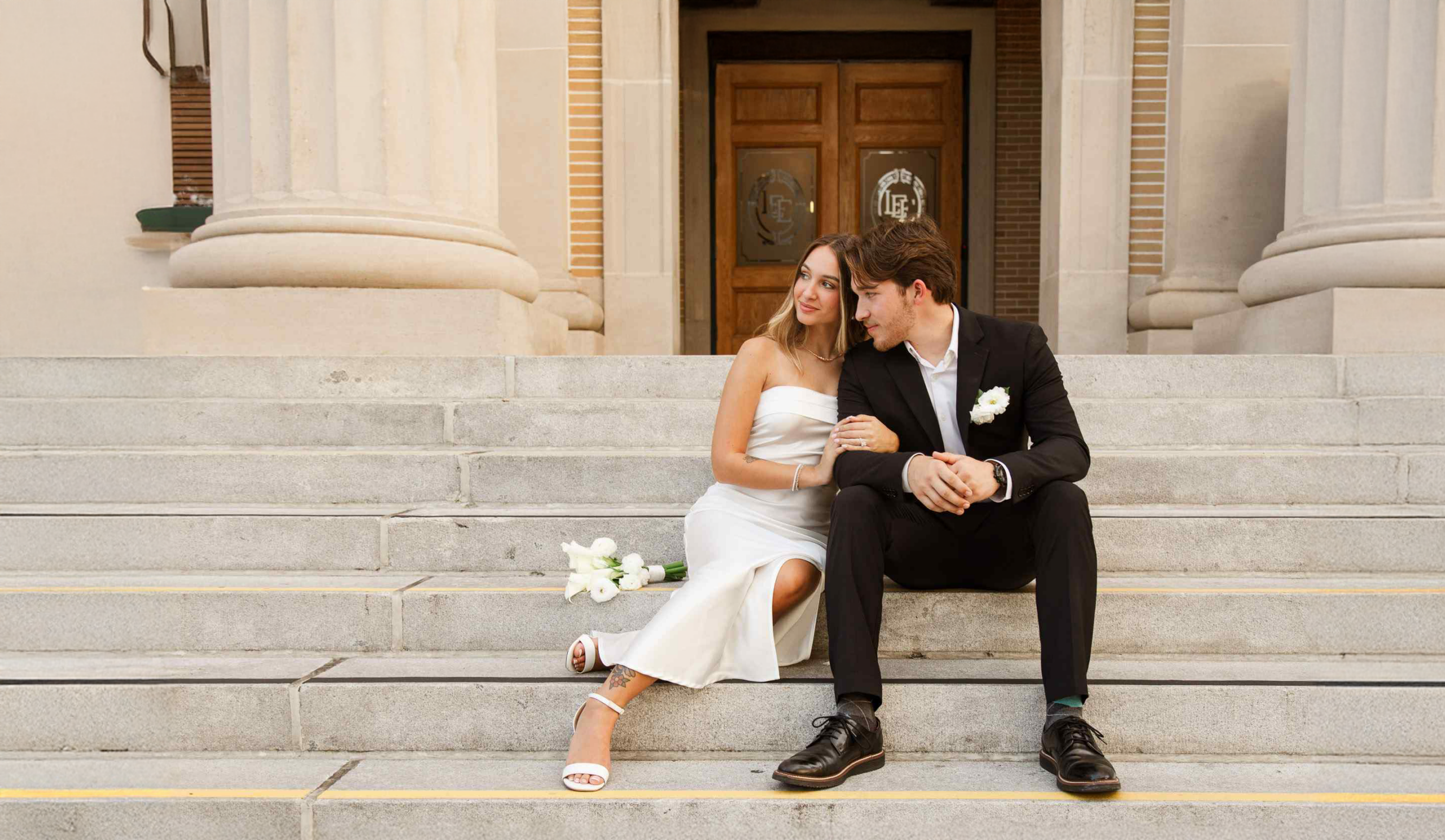 Bride and groom sitting on steps of the Old Lee County Courthouse