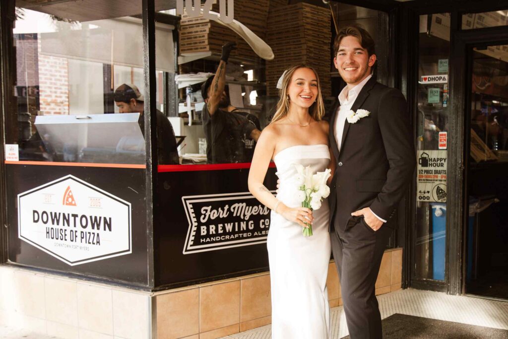 Bride and groom smile outside Downtown House of Pizza