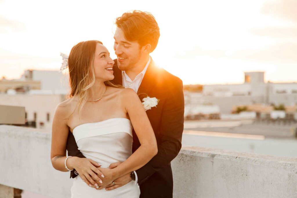 Golden hour flare behind laughing bride and groom