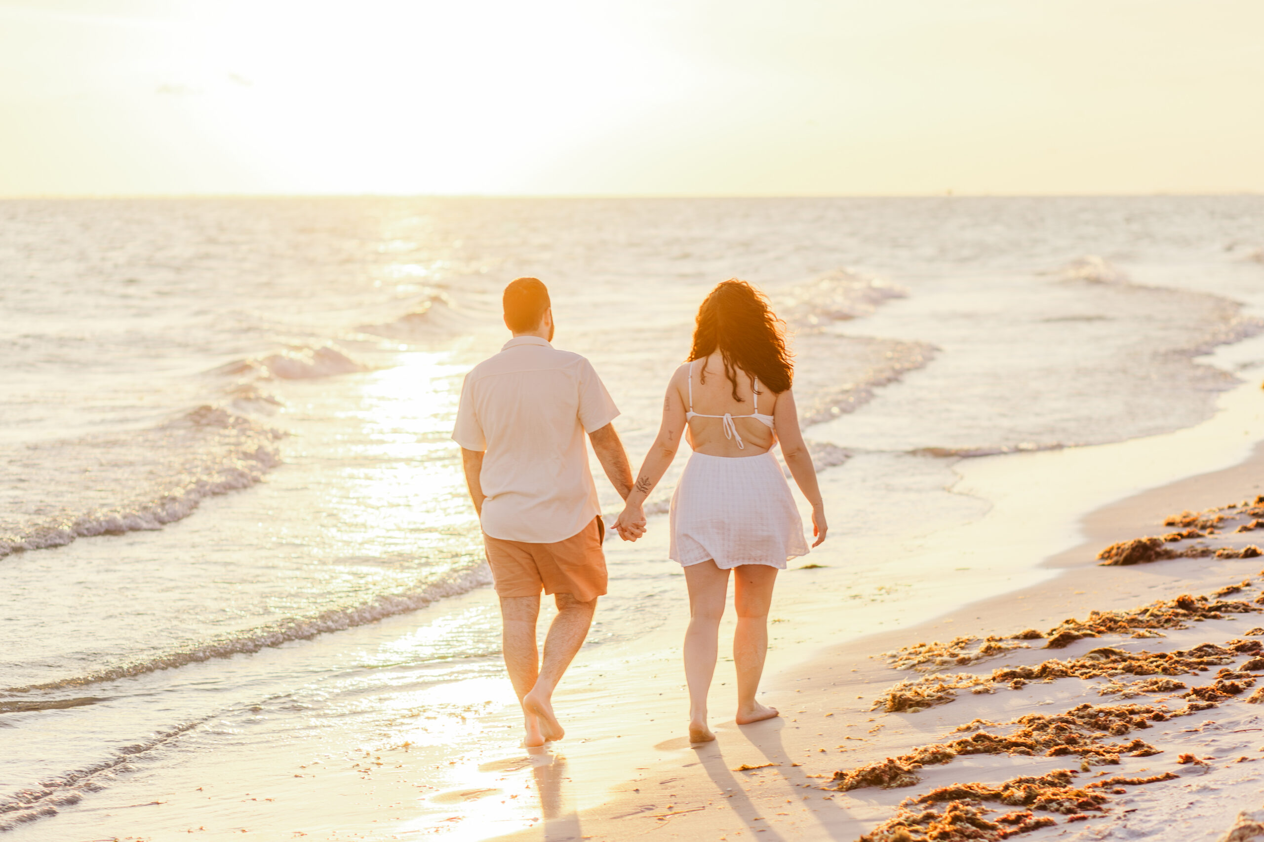 Couple walking on the beach at sunset after proposal