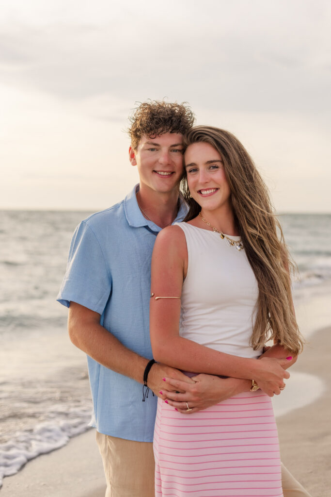 Couple poses for a photo in front of the beach