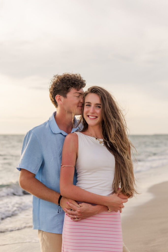 Man nuzzles fiancee's cheek on the beach
