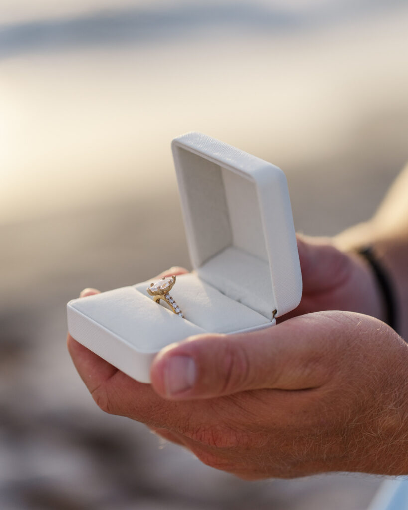 Close up of man holding engagement ring in a white ring box
