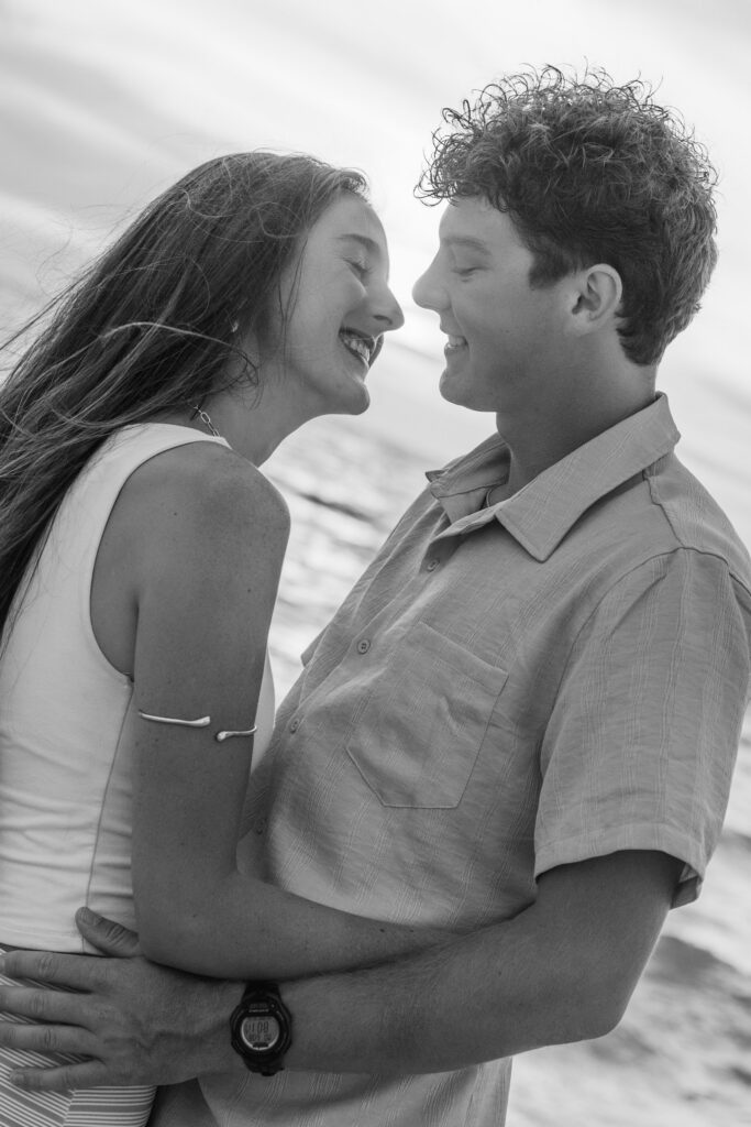 Black and white image, couple smiles at each other with their faces close together
