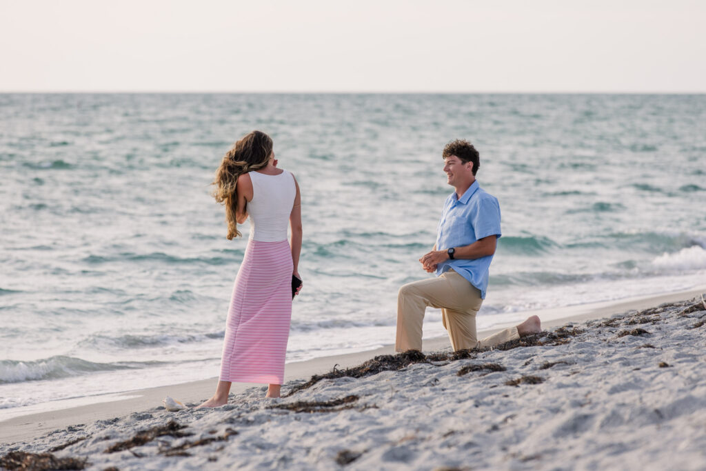 Woman turns from seashell to her boyfriend behind her on one knee