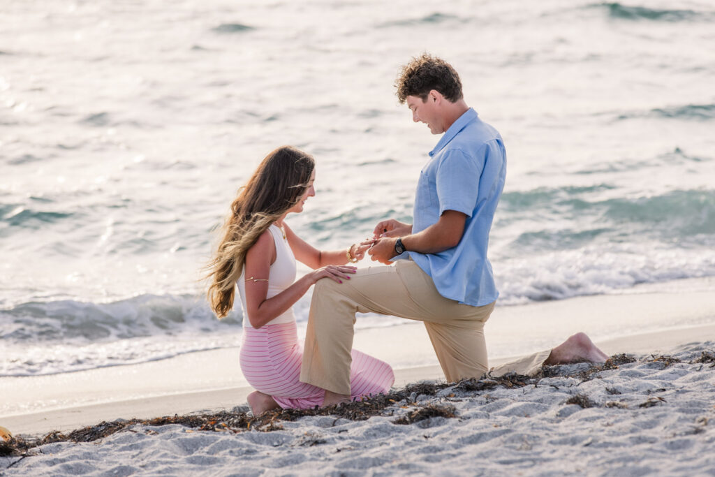 Woman kneels down with boyfriend on his knee while he puts engagement ring on her finger