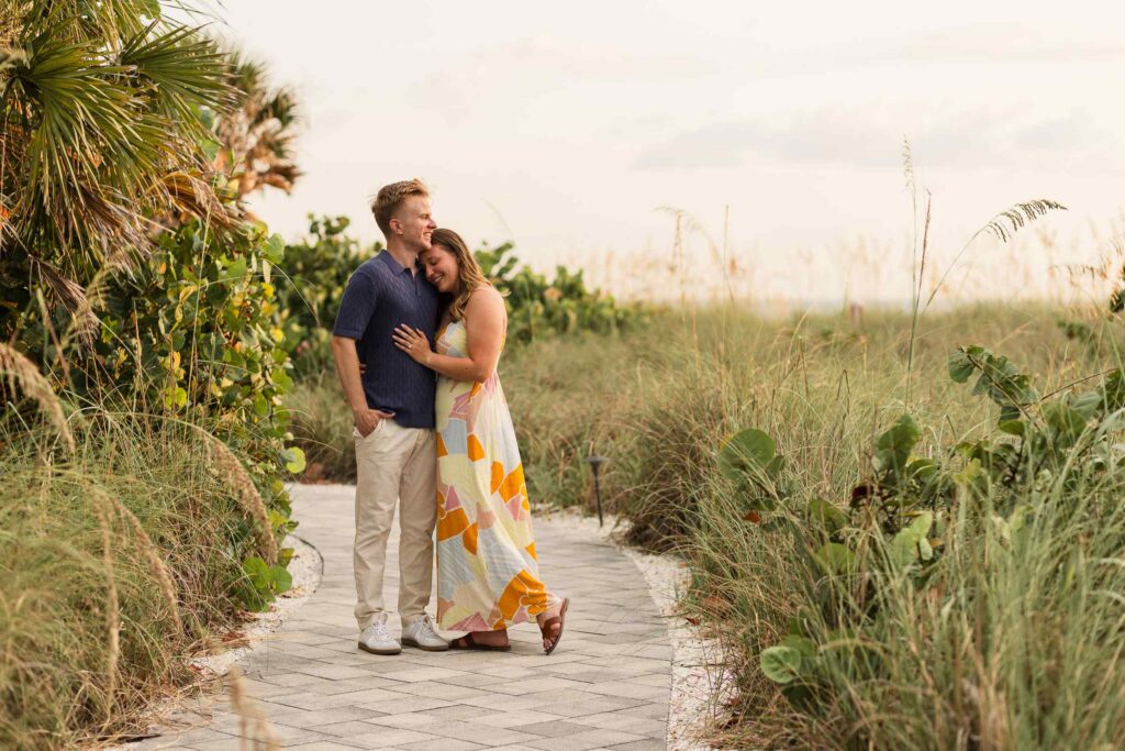 Couple posing in the middle of a path surrounded by beach grass
