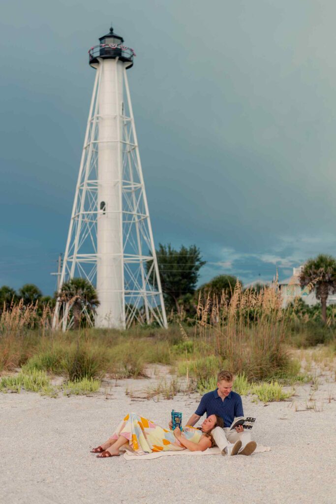 Couple seated on a blanket reading together at the base of the Gasparilla Lighthouse