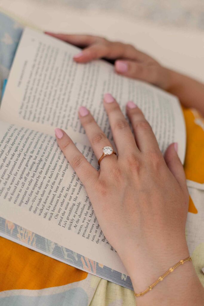 Close up of woman's hand and engagement ring holding a book open