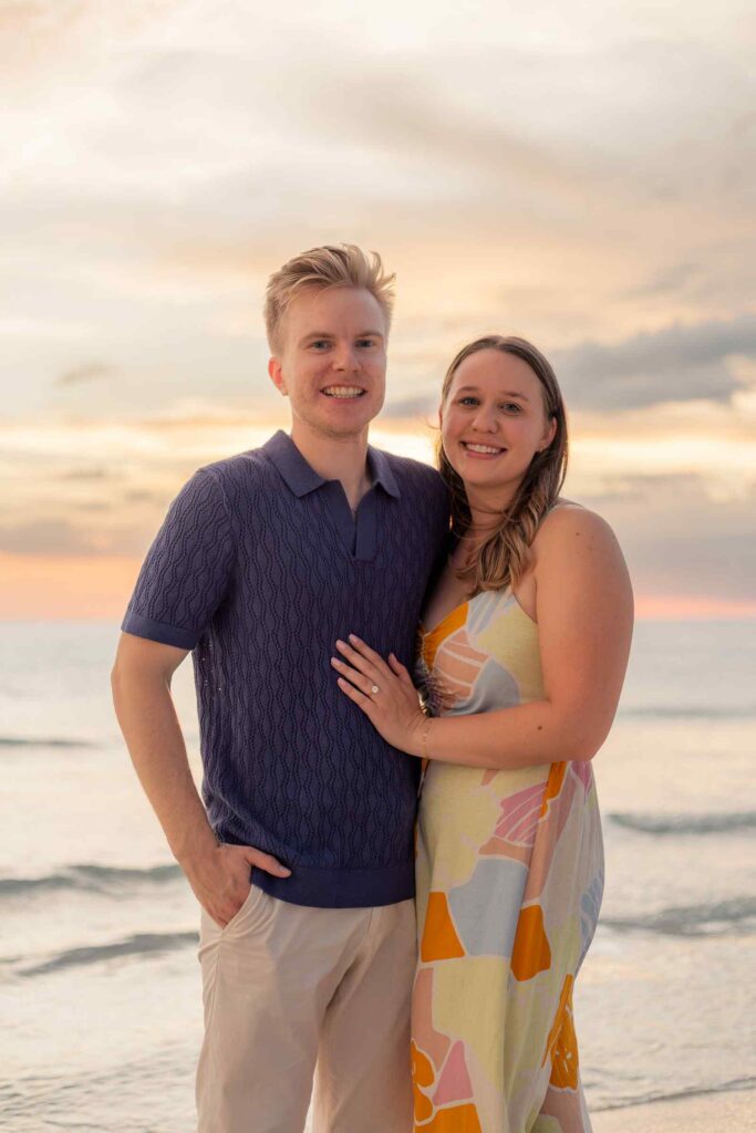 Couple posing in front of the beach sunset