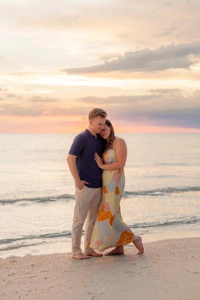 Couple posing in front of the beach sunset