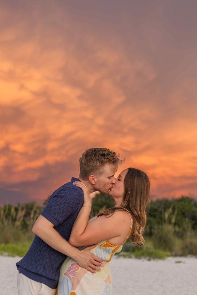 Couple kissing with bright orange clouds above them