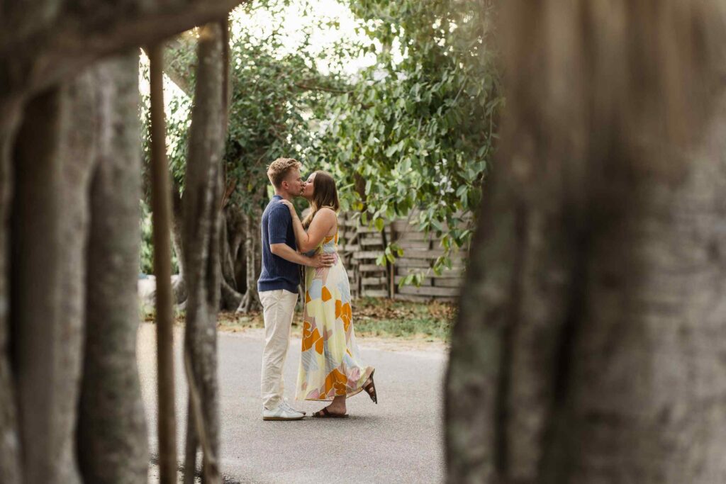 Couple kissing in the background of banyan trunks in the foreground