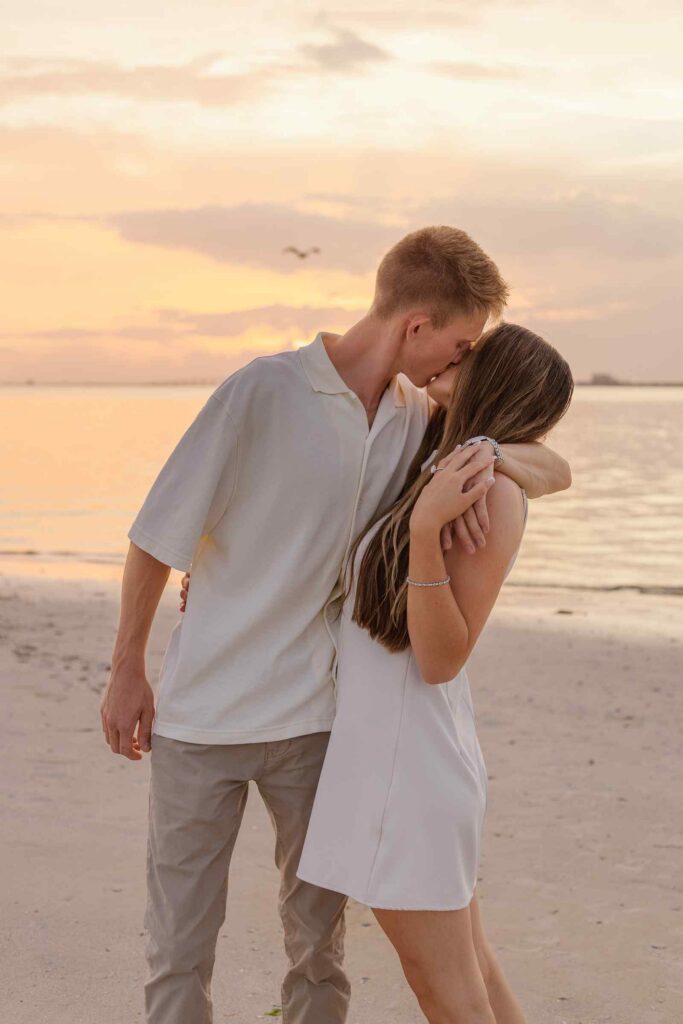 Man kisses fiancée with his arm around her shoulder