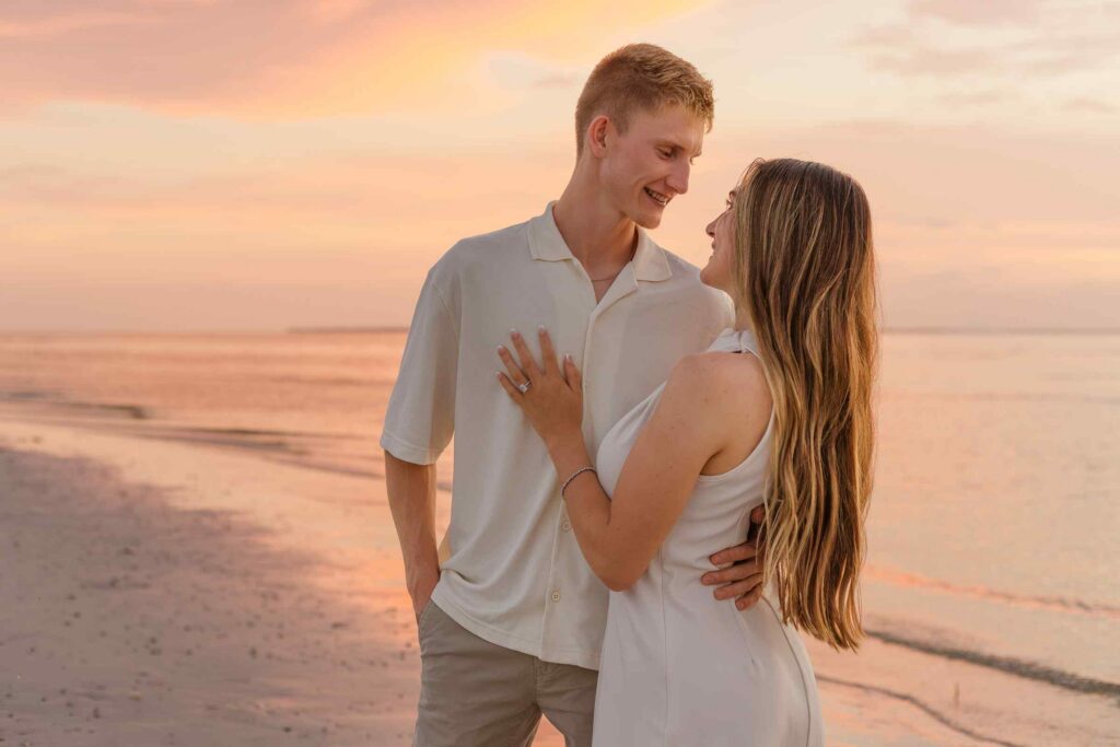 Couple smiling at each other with a vibrant sunset in the background